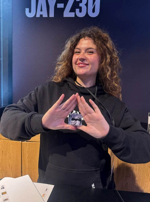 The supplied woman in a black hoodie holding an Album Tag